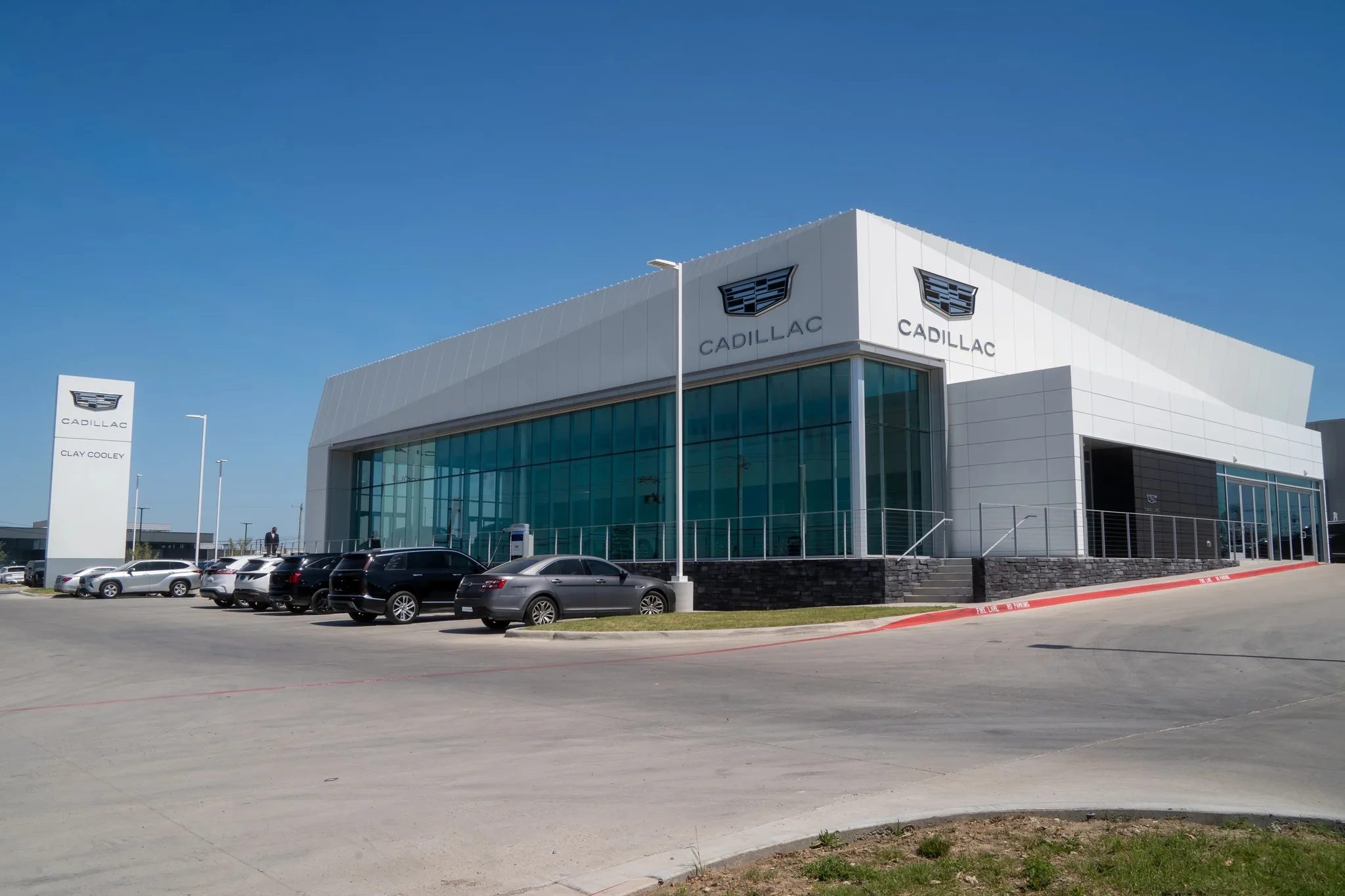 Exterior of Clay Cooley Cadillac in Mesquite, Texas, with white metal cladding, a glass curtain wall and pylon sign, built by The Charles Morgan Group