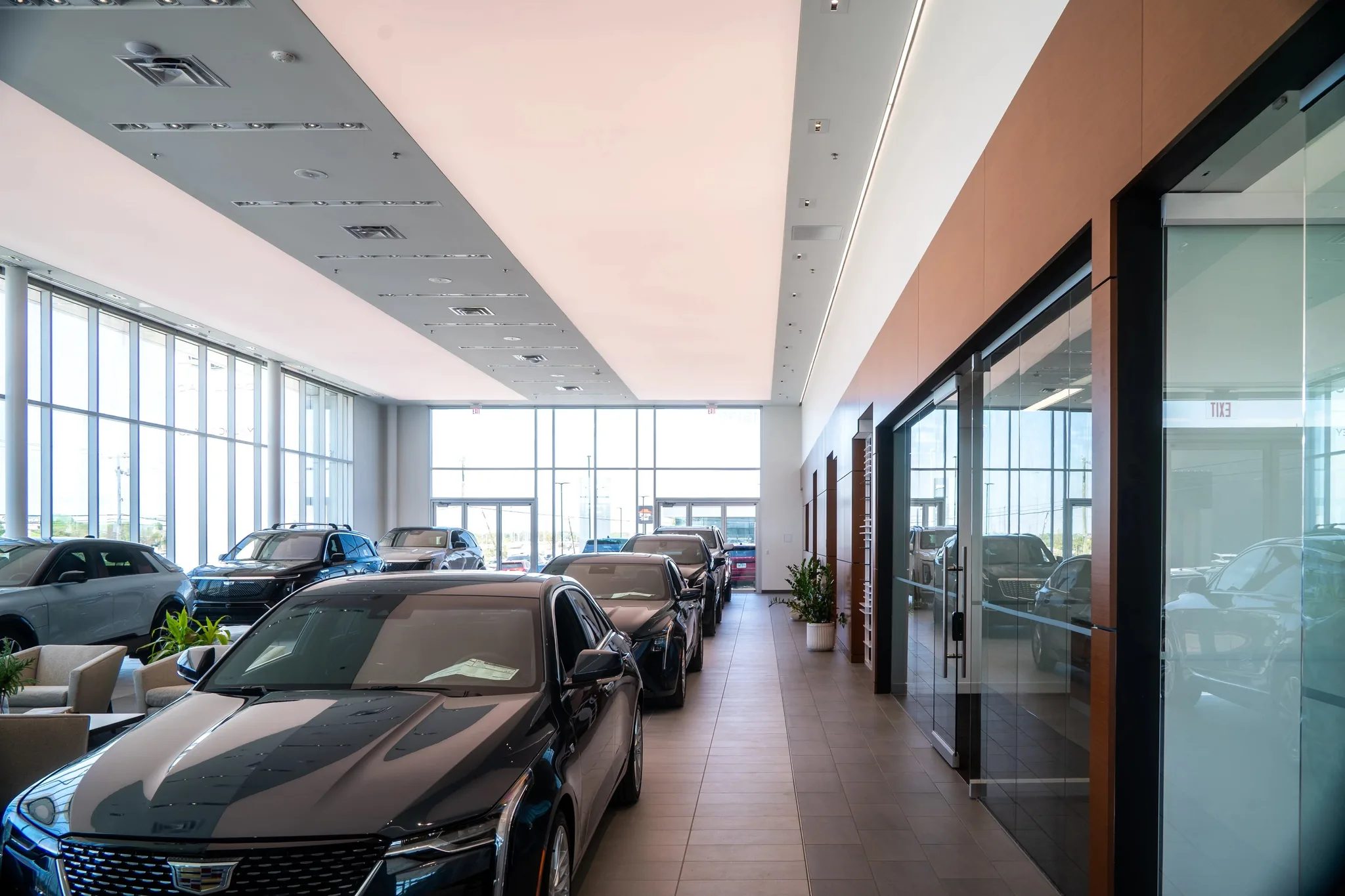 Row of new Cadillacs beside glass-fronted offices in the showroom at Clay Cooley Cadillac in Mesquite, Texas, built by The Charles Morgan Group