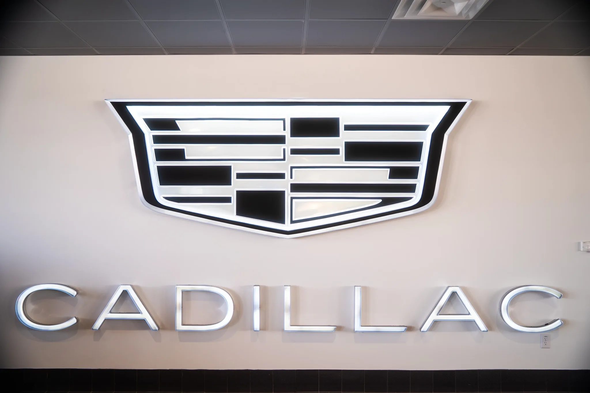 Backlit Cadillac crest and lettering on the showroom wall at Clay Cooley Cadillac in Mesquite, Texas, built by The Charles Morgan Group
