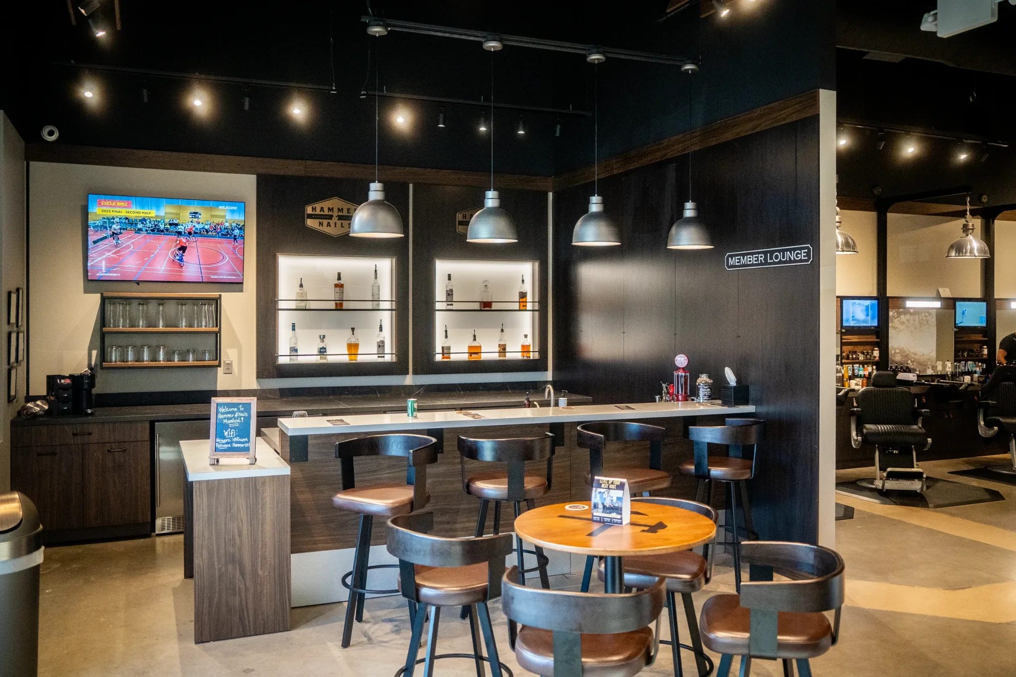 Member lounge bar at Hammer & Nails Grooming Shop for Guys in Mansfield, Texas, with backlit liquor shelves, built by The Charles Morgan Group