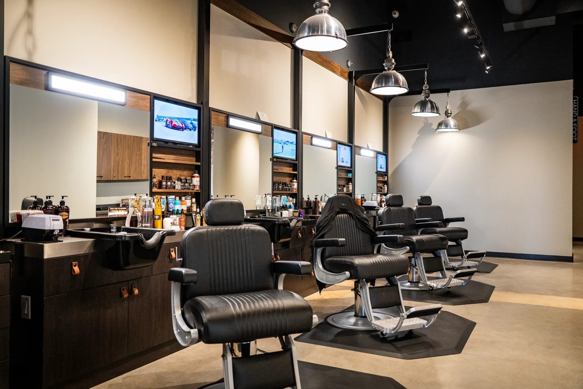 Barber stations with leather chairs, mirrors and TVs at Hammer & Nails Grooming Shop for Guys in Mansfield, Texas, built by The Charles Morgan Group