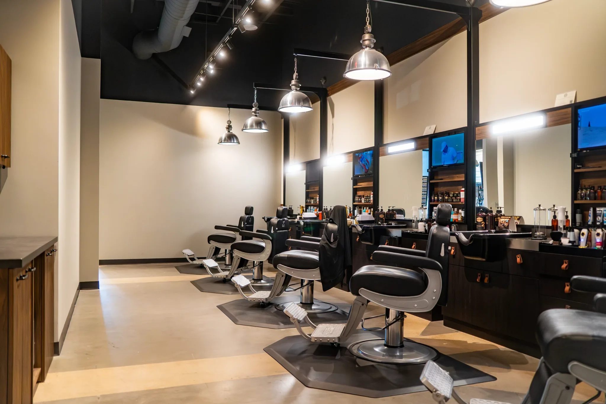 Row of barber chairs under industrial pendant lights at Hammer & Nails Grooming Shop for Guys in Mansfield, Texas, built by The Charles Morgan Group