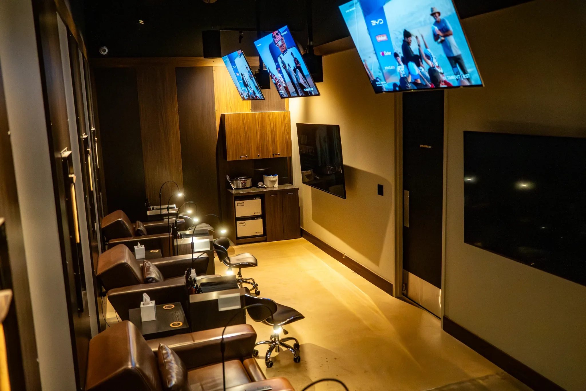 Treatment room with leather recliners and overhead TVs at Hammer & Nails in Mansfield, Texas, built by The Charles Morgan Group
