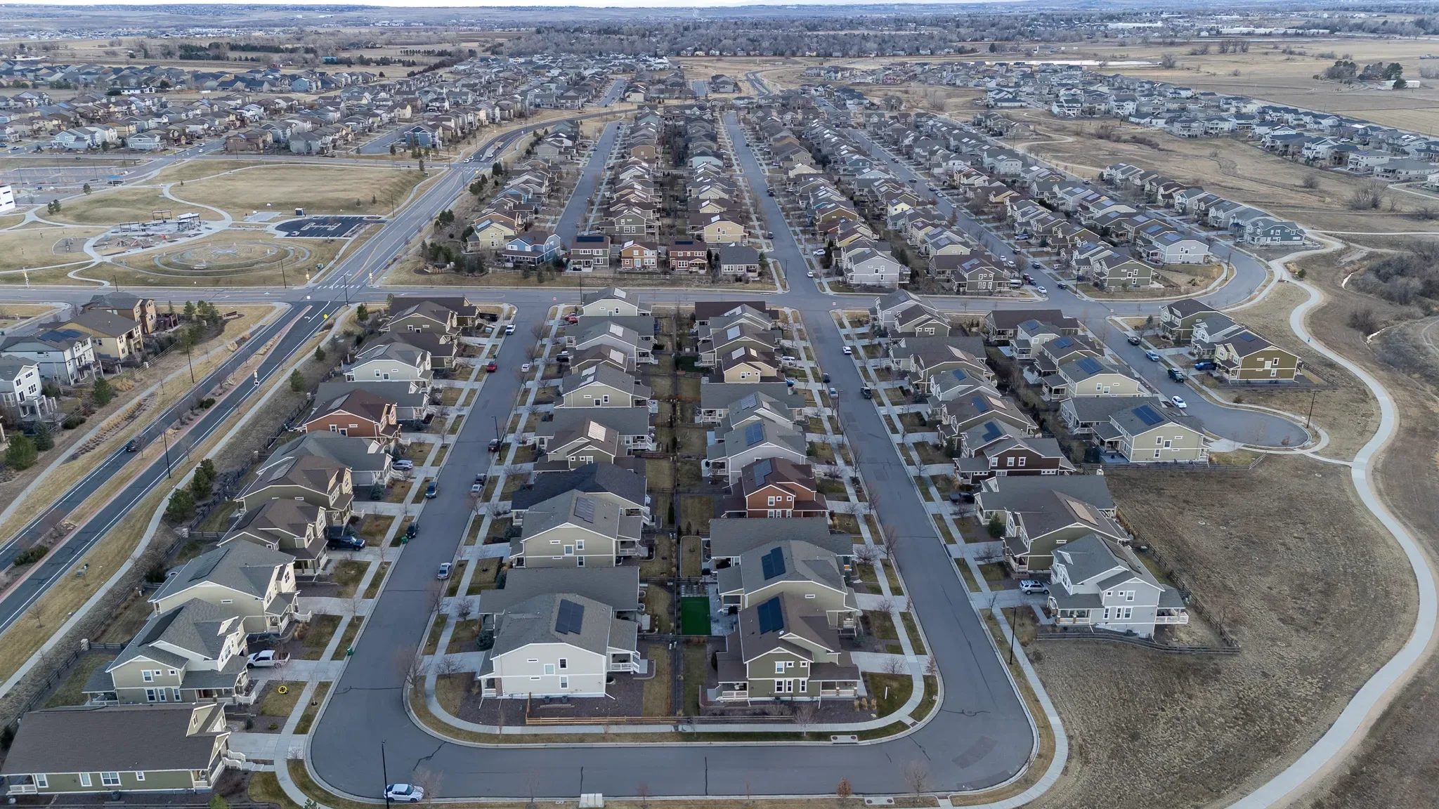 Drone view over rows of two-story suburban homes and a neighborhood park in a Denver-area subdivision in winter.