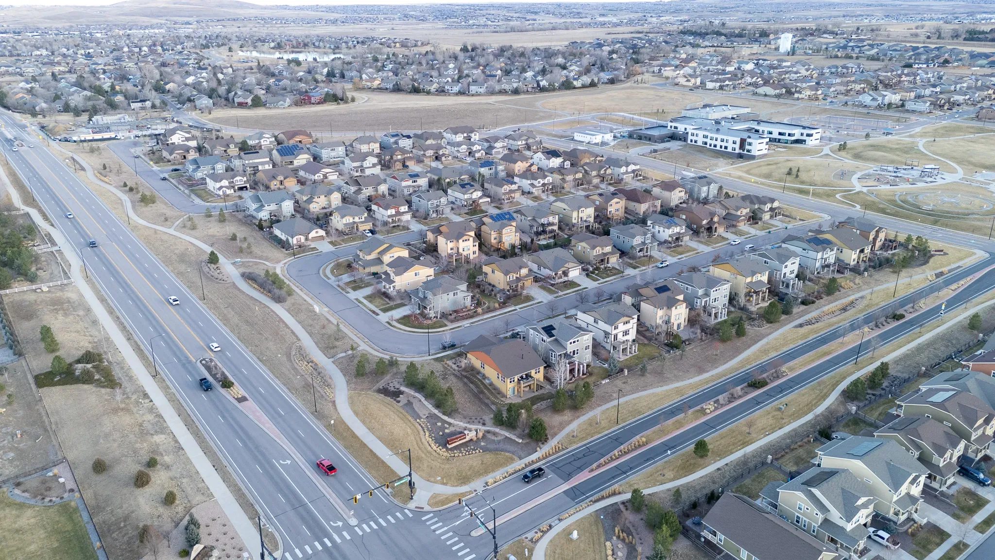 Aerial view of a subdivision block beside a divided arterial road and signalized intersection in the Denver area.