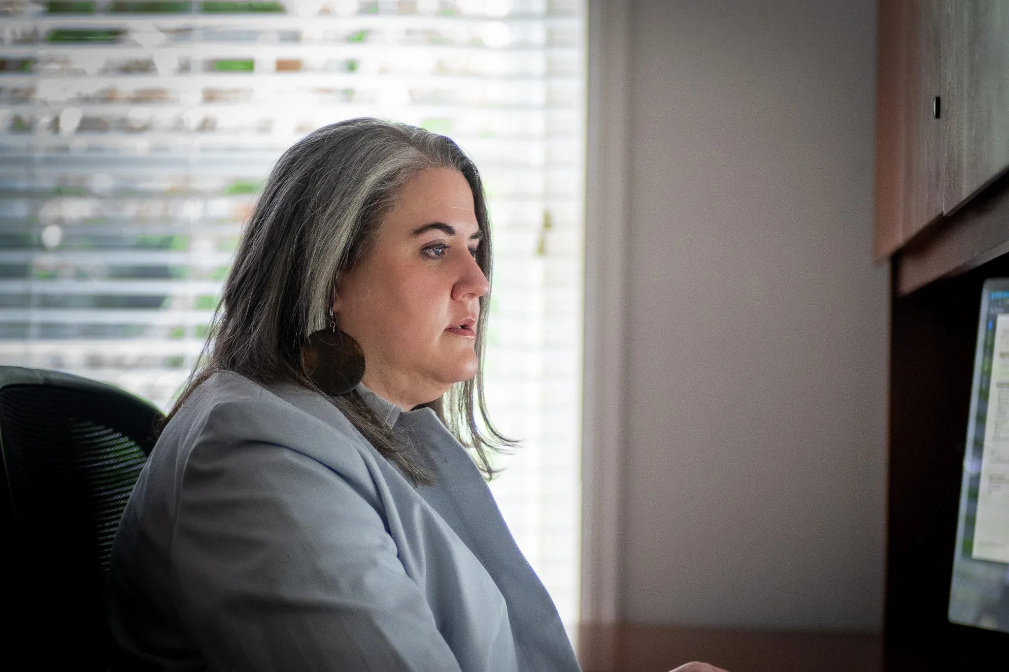 Marcia Forney, Paralegal, in profile at a desk beside a bright window at Nelson Law Firm.