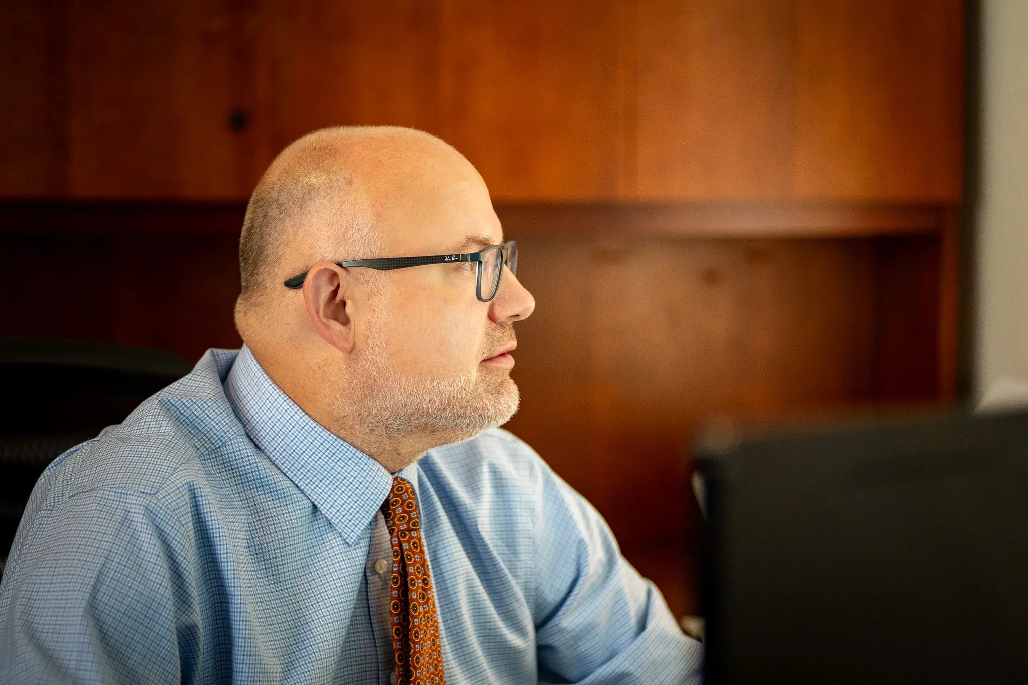 Kevin P. Ahearn, Attorney, in profile at a desk at Nelson Law Firm, looking at a monitor.