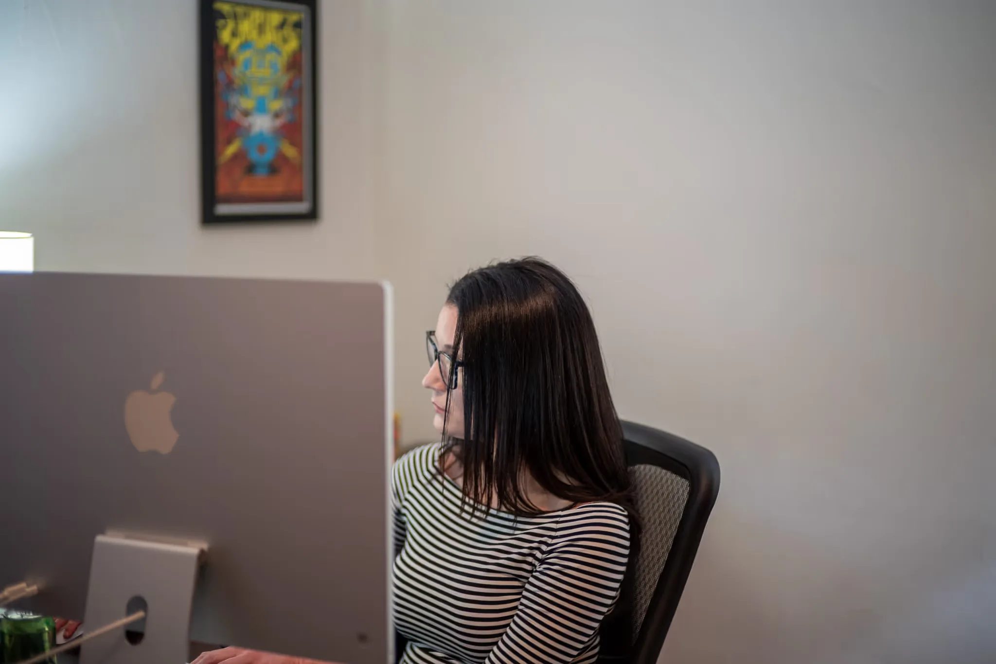 A staff member in a striped top faces an iMac screen in a Nelson Law Firm office.