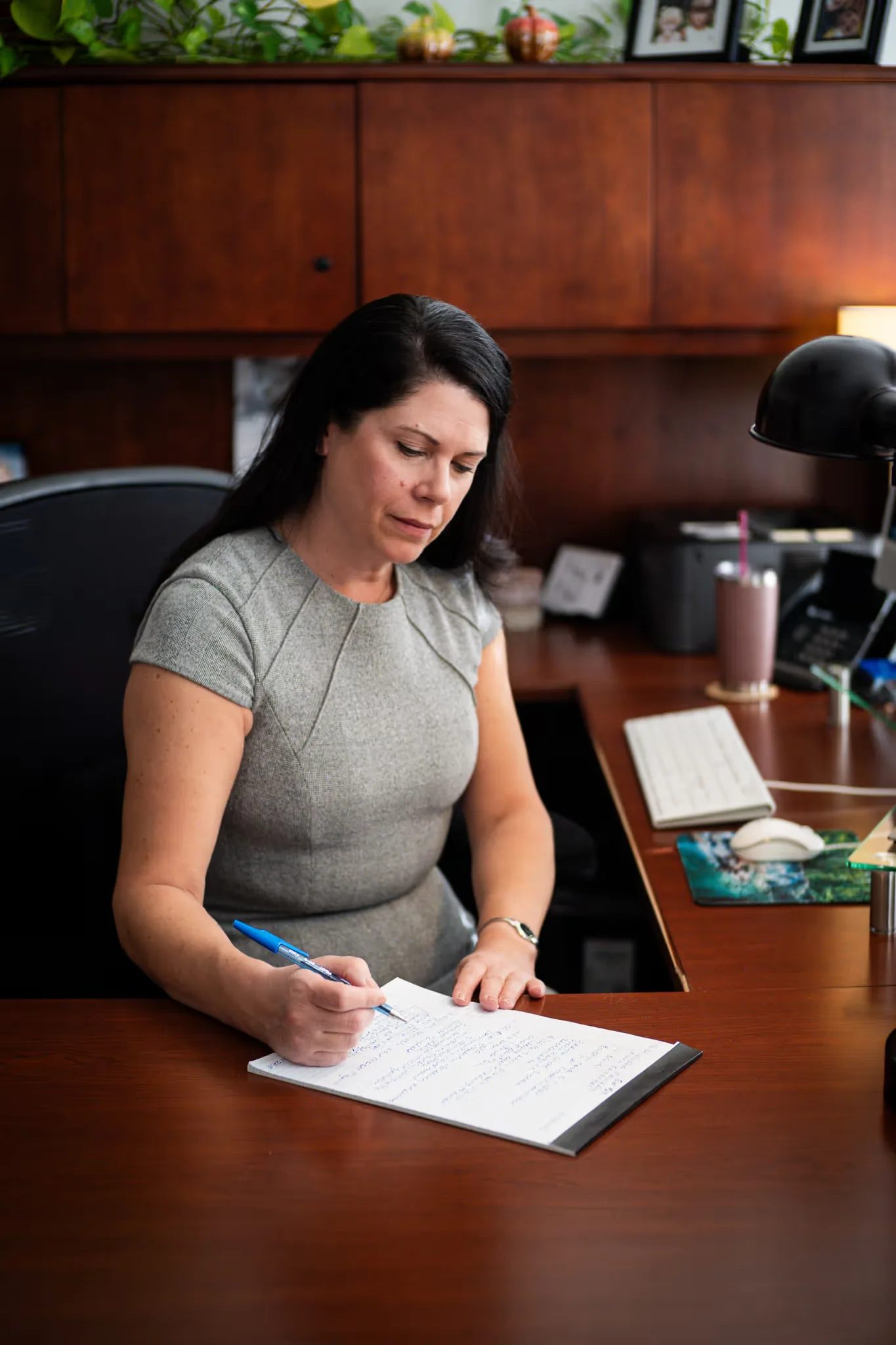 A staff member reviews a handwritten document at a wood desk in a Nelson Law Firm office.