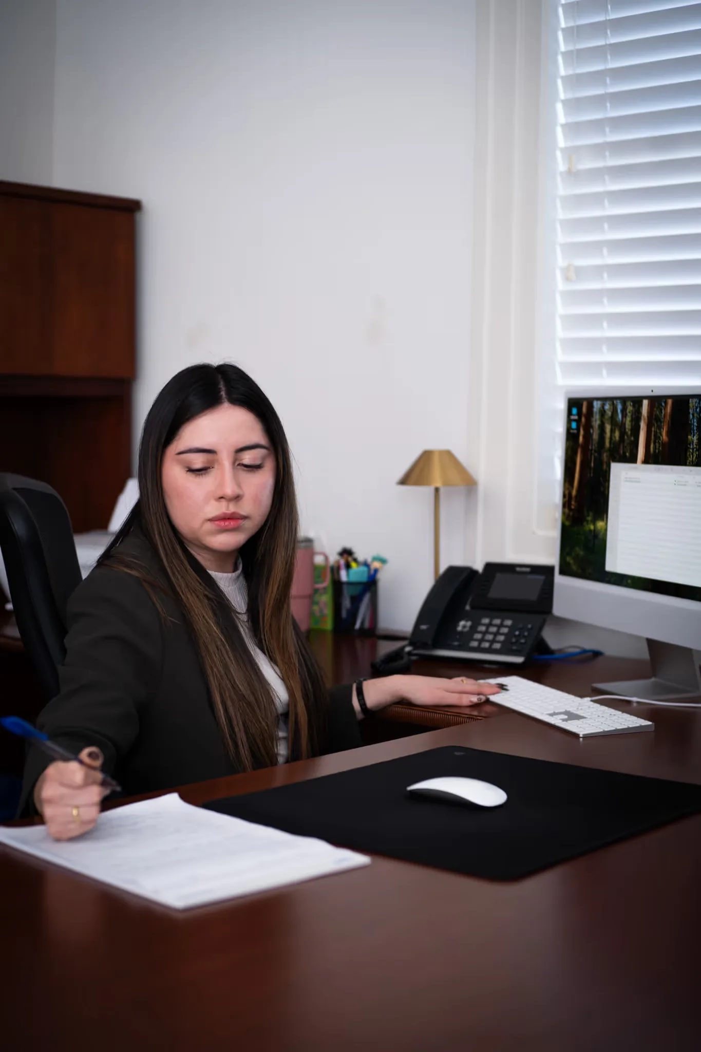 Mariana Gonzalez, Paralegal at Nelson Law Firm, marks up a printed document at a desk with an iMac.