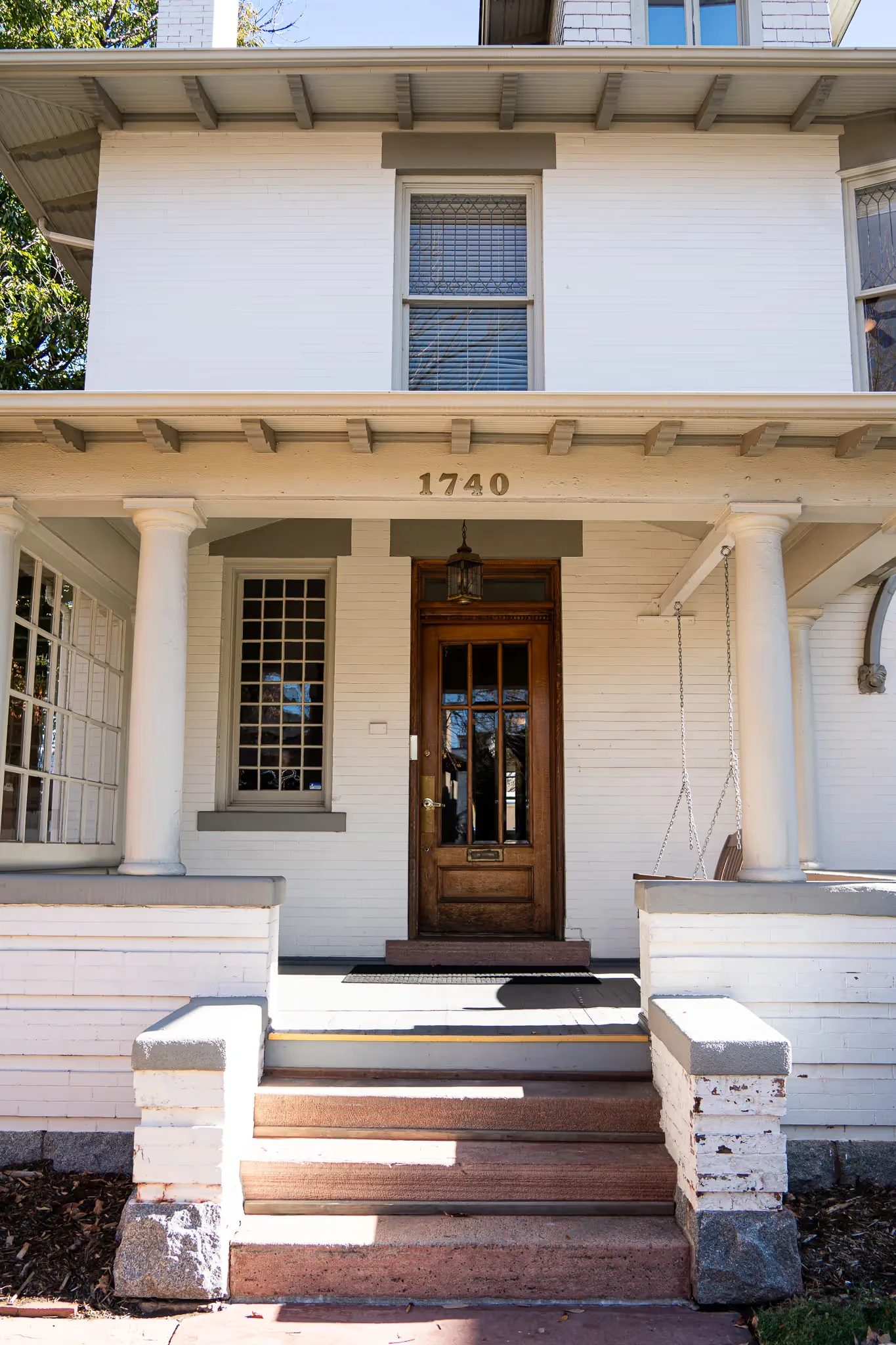 Front entrance of the Nelson Law Firm office at 1740 N High Street, Denver, with a wooden door, porch columns and a porch swing