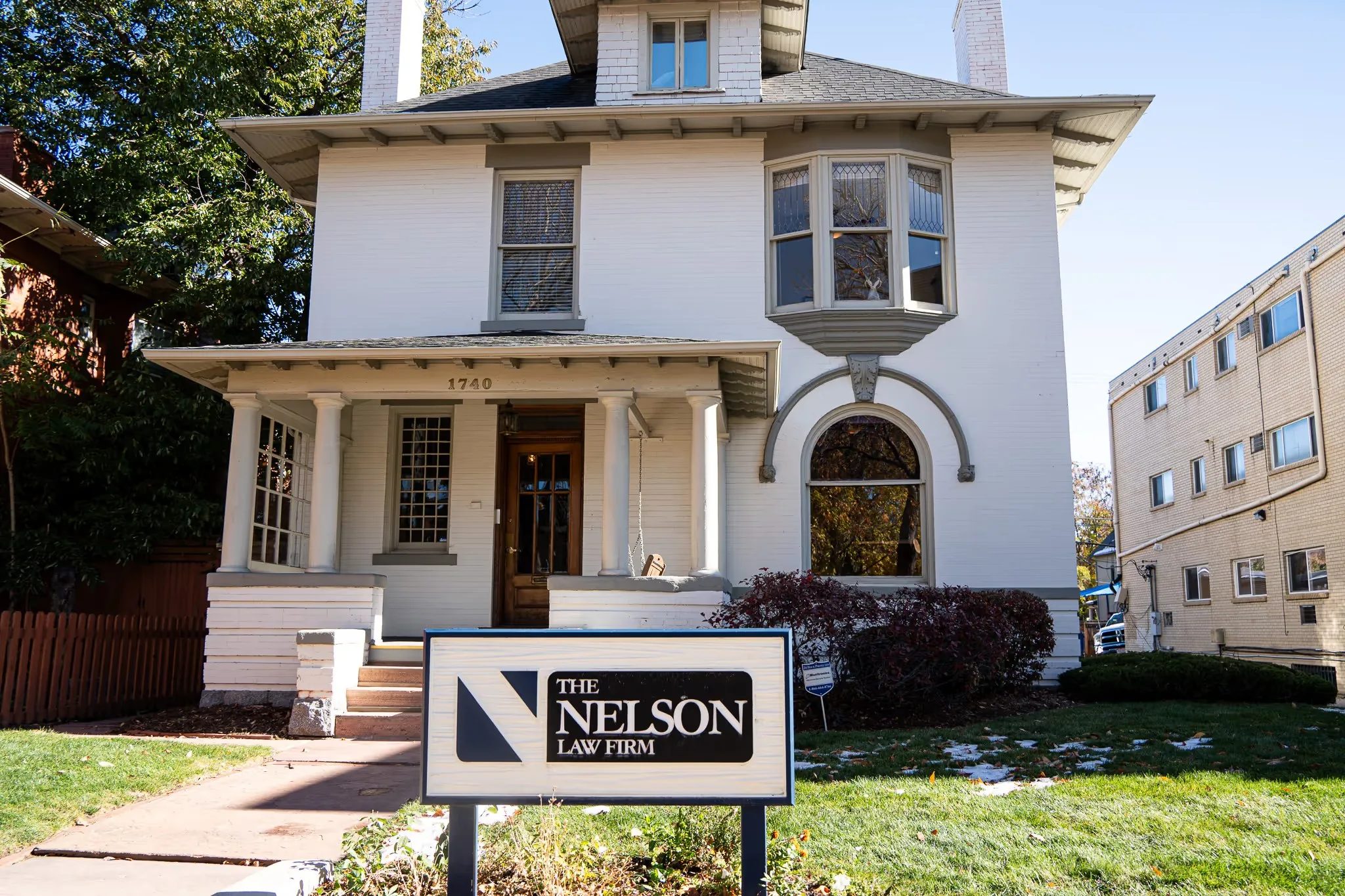 Historic white two-story house at 1740 N High Street with the Nelson Law Firm sign on the front lawn in Denver.