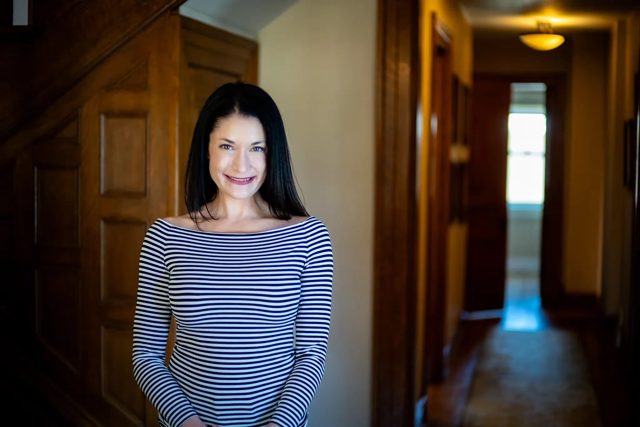 A Nelson Law Firm staff member in a striped top smiling in a wood-trimmed hallway of the firm's historic Denver office