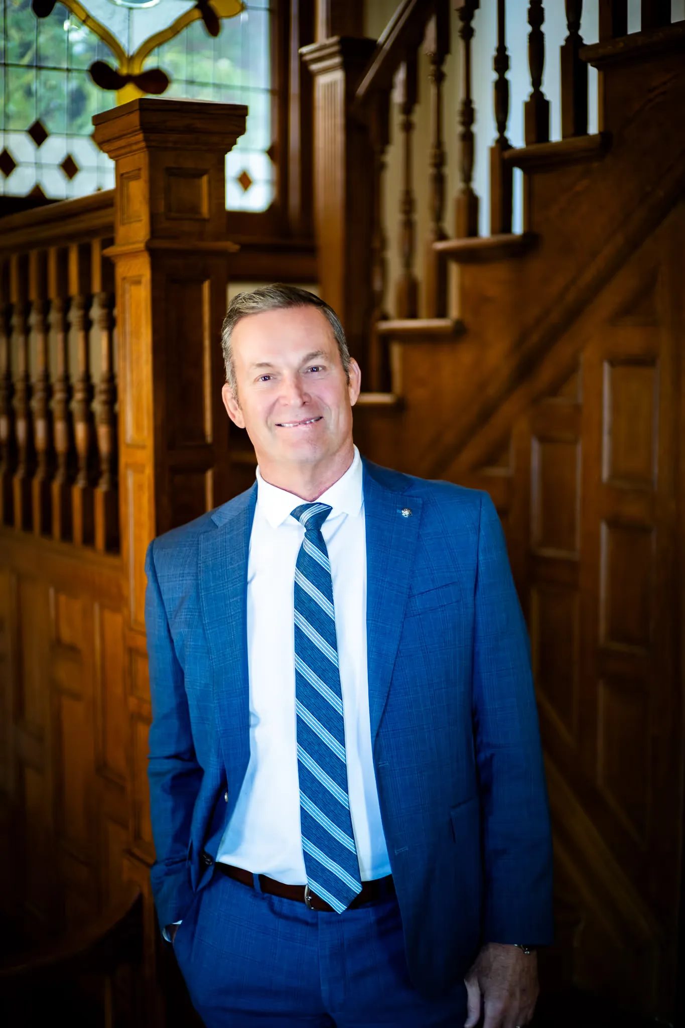 Mark W. Nelson, founder of Nelson Law Firm, standing with one hand in a pocket at the firm's oak staircase in Denver