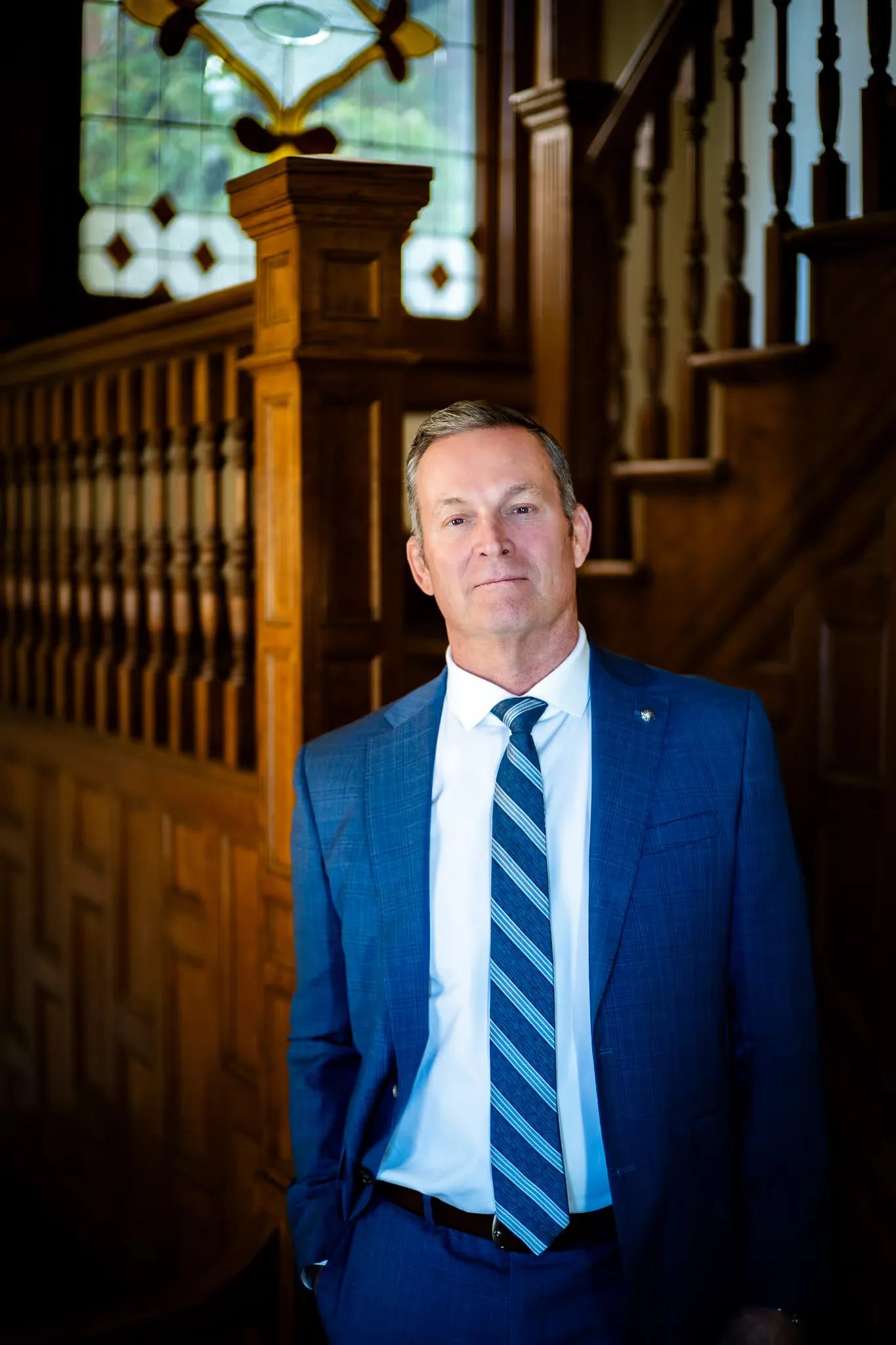 Mark W. Nelson, founder of Nelson Law Firm, standing at the stained-glass staircase of the firm's historic Denver office