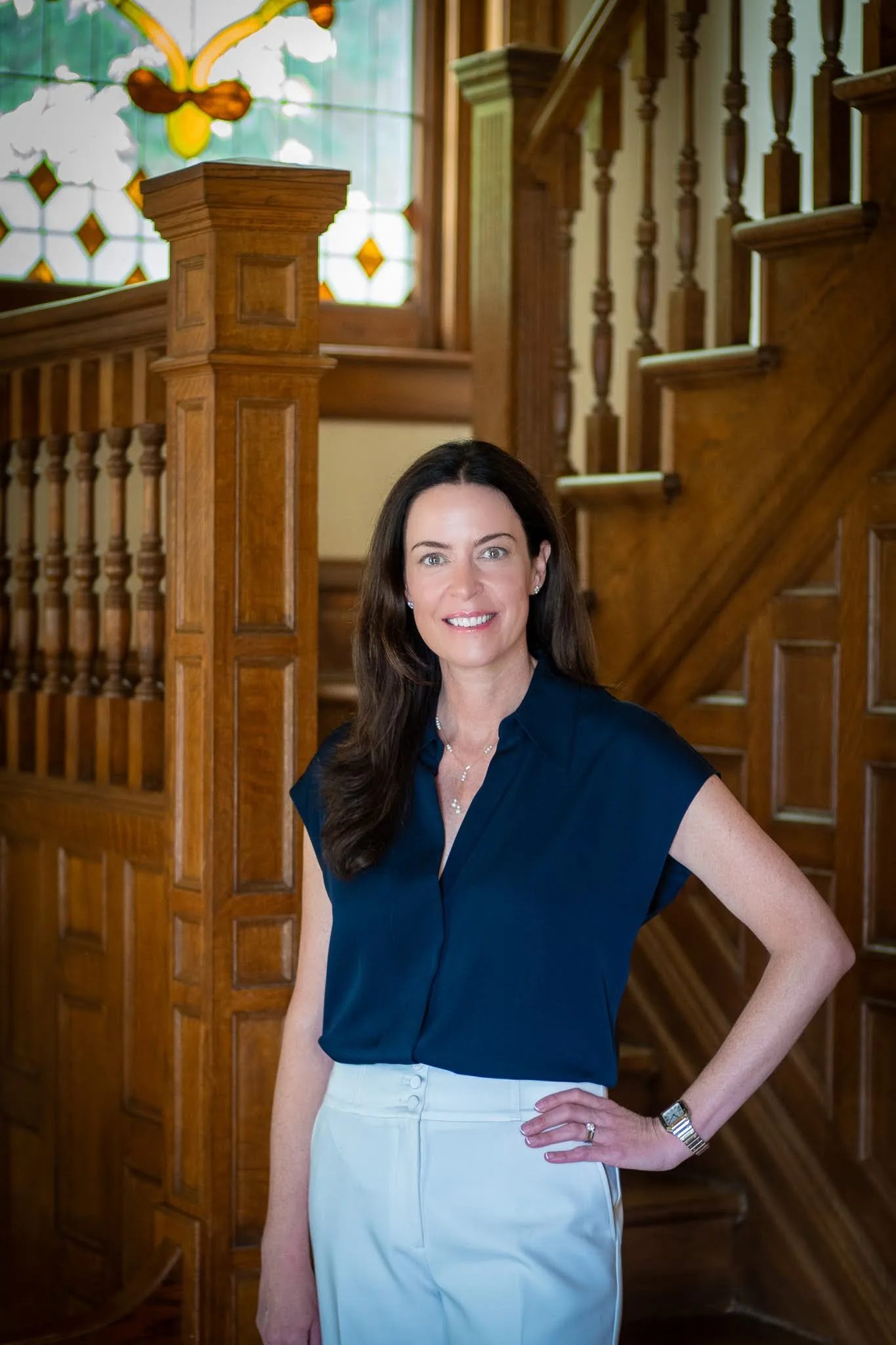 Colleen S. Nelson, co-founder of Nelson Law Firm, standing at the oak staircase of the firm's historic Denver office