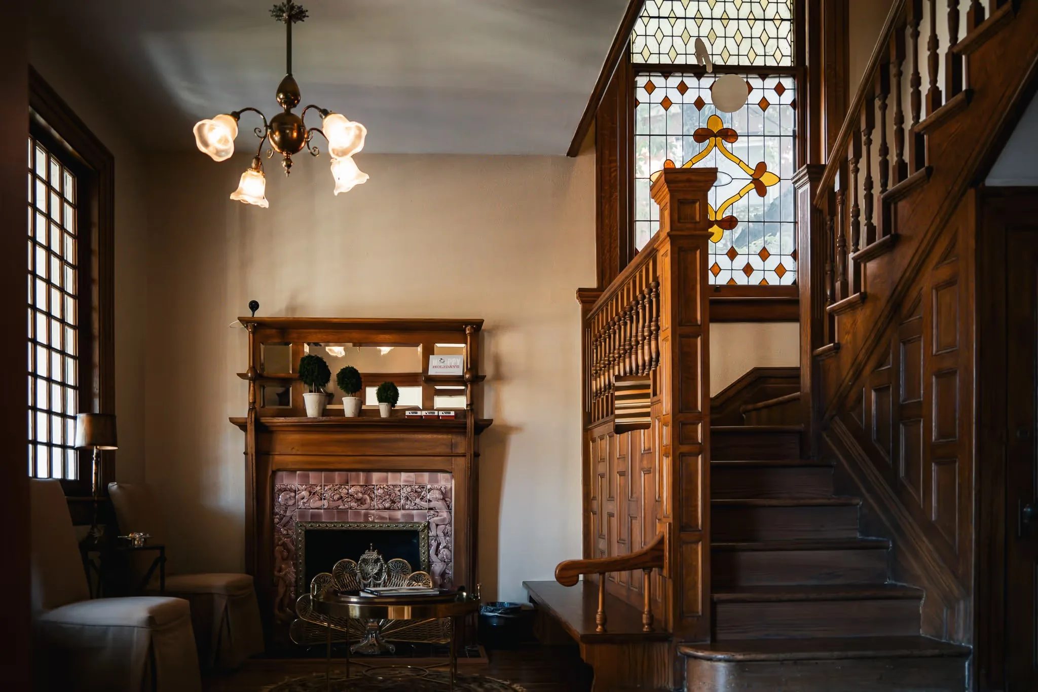 Reception parlor with chandelier, antique fireplace and stained-glass staircase window at Nelson Law Firm in Denver.