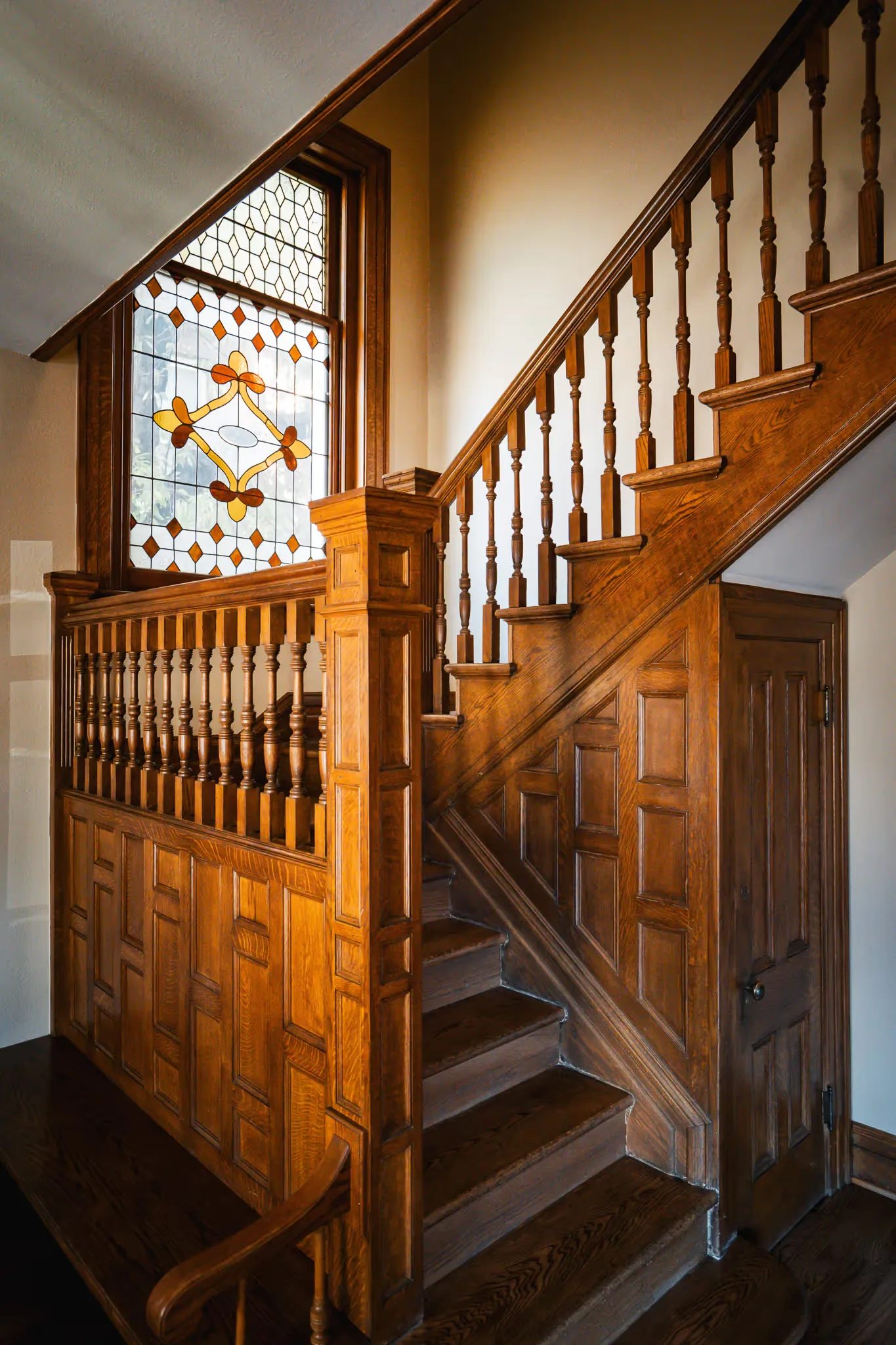 Oak staircase with turned balusters, paneled wainscot and a stained-glass window in Nelson Law Firm's historic Denver office.
