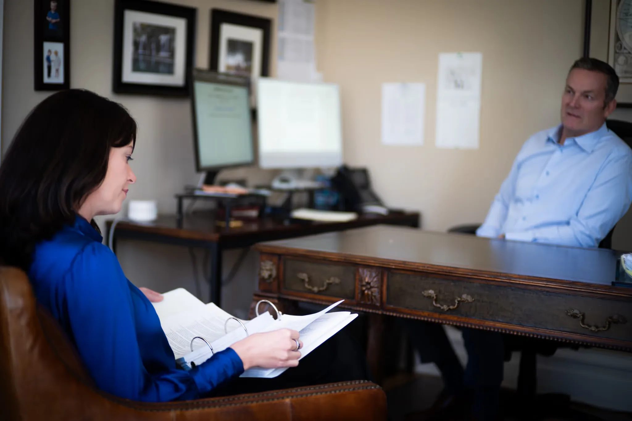 Colleen S. Nelson reviewing documents in an armchair while Mark W. Nelson sits at a desk in the Nelson Law Firm office