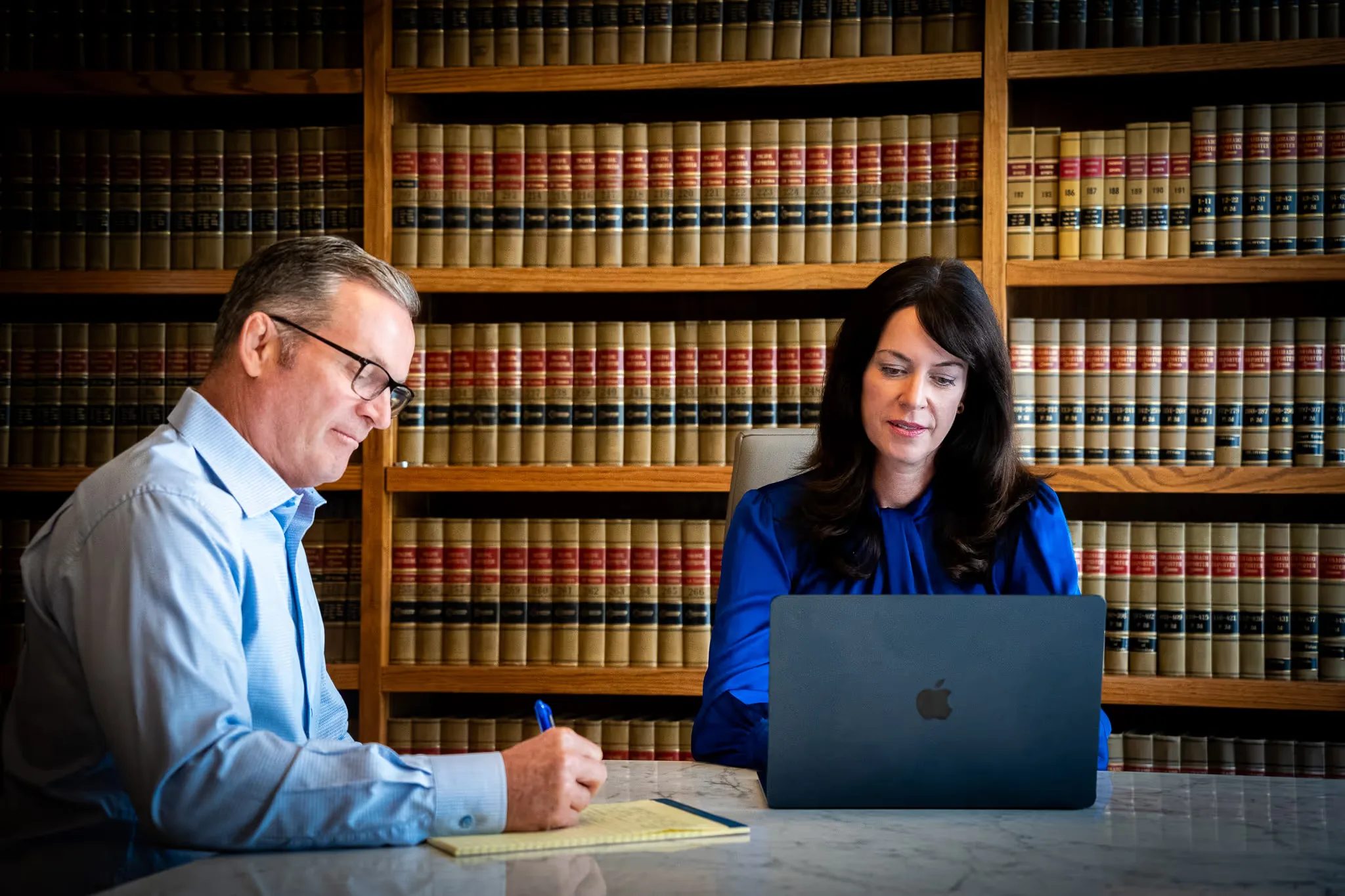 Mark W. Nelson and Colleen S. Nelson working at a conference table with a laptop and legal pad in front of law library shelves