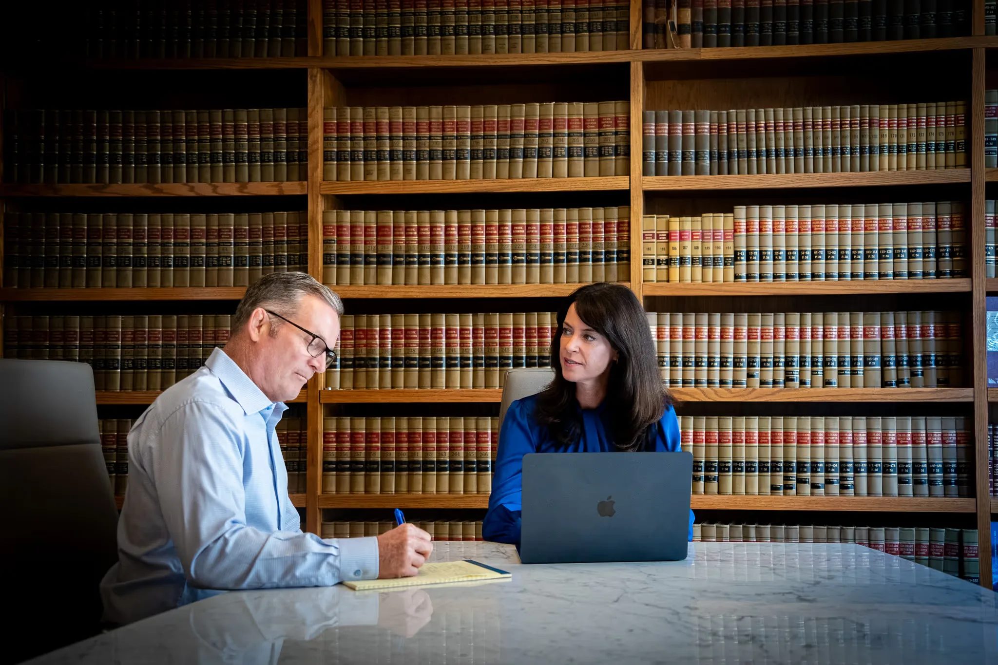 Wide view of Mark W. Nelson and Colleen S. Nelson at a conference table in the Nelson Law Firm library, bookshelves floor to ceiling