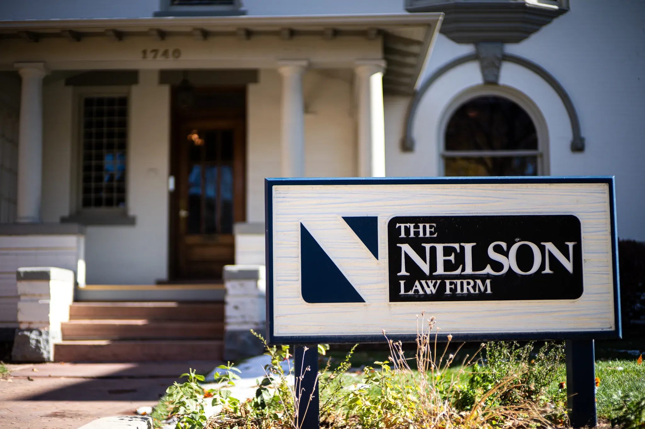 Nelson Law Firm sign in front of the columned porch and wooden front door of the firm's historic Denver office.