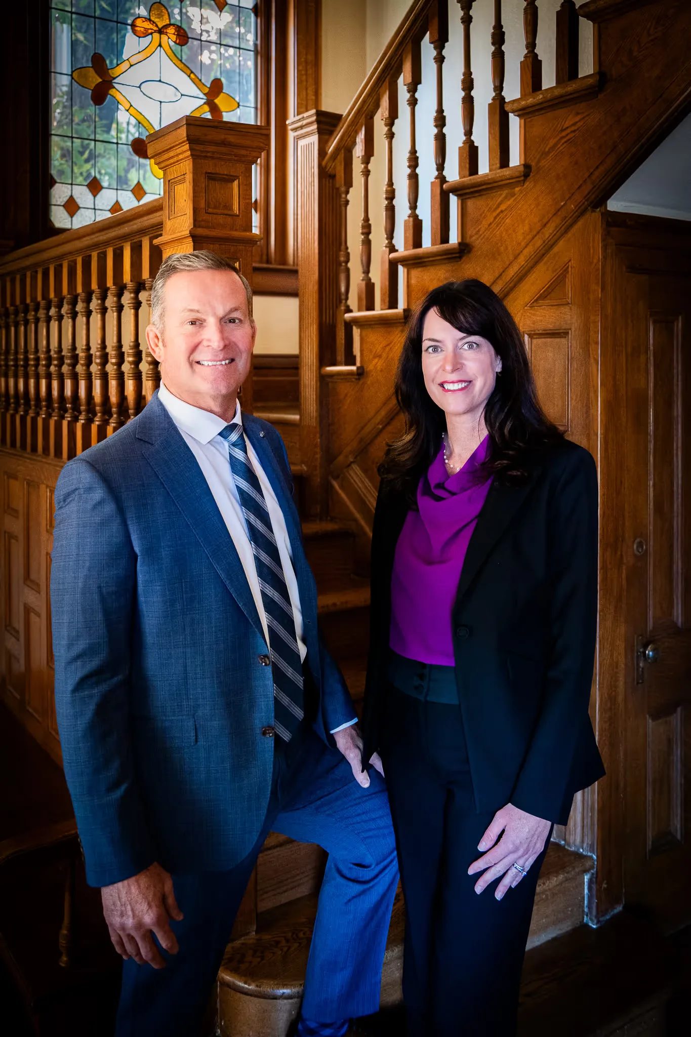 Mark W. Nelson and Colleen S. Nelson, founders of Nelson Law Firm, standing together at the oak staircase of the firm's Denver office