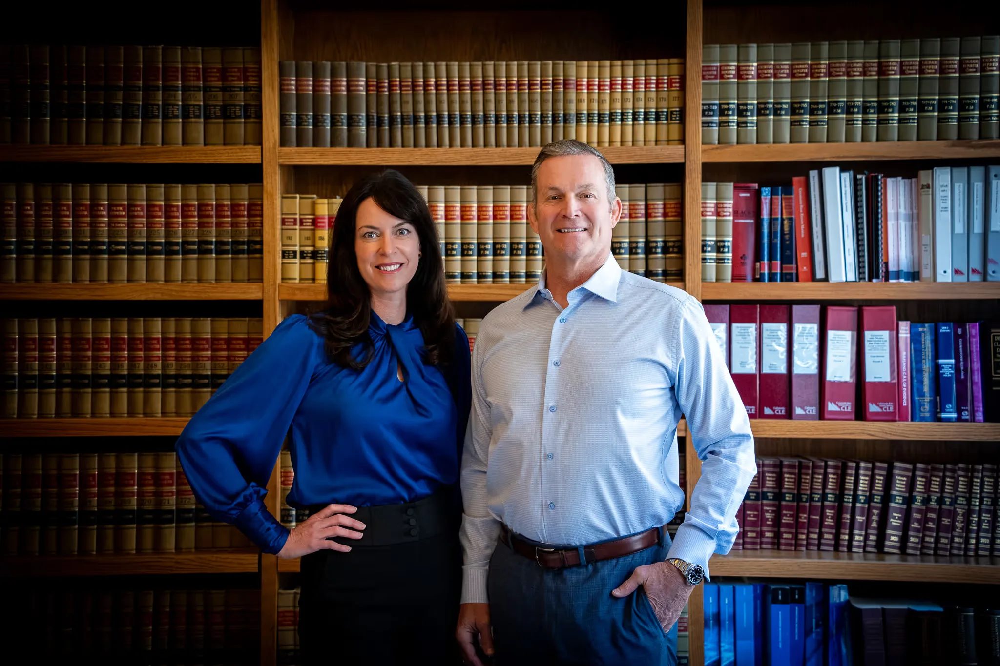 Colleen S. Nelson and Mark W. Nelson, founders of Nelson Law Firm, standing in front of law library shelves in Denver