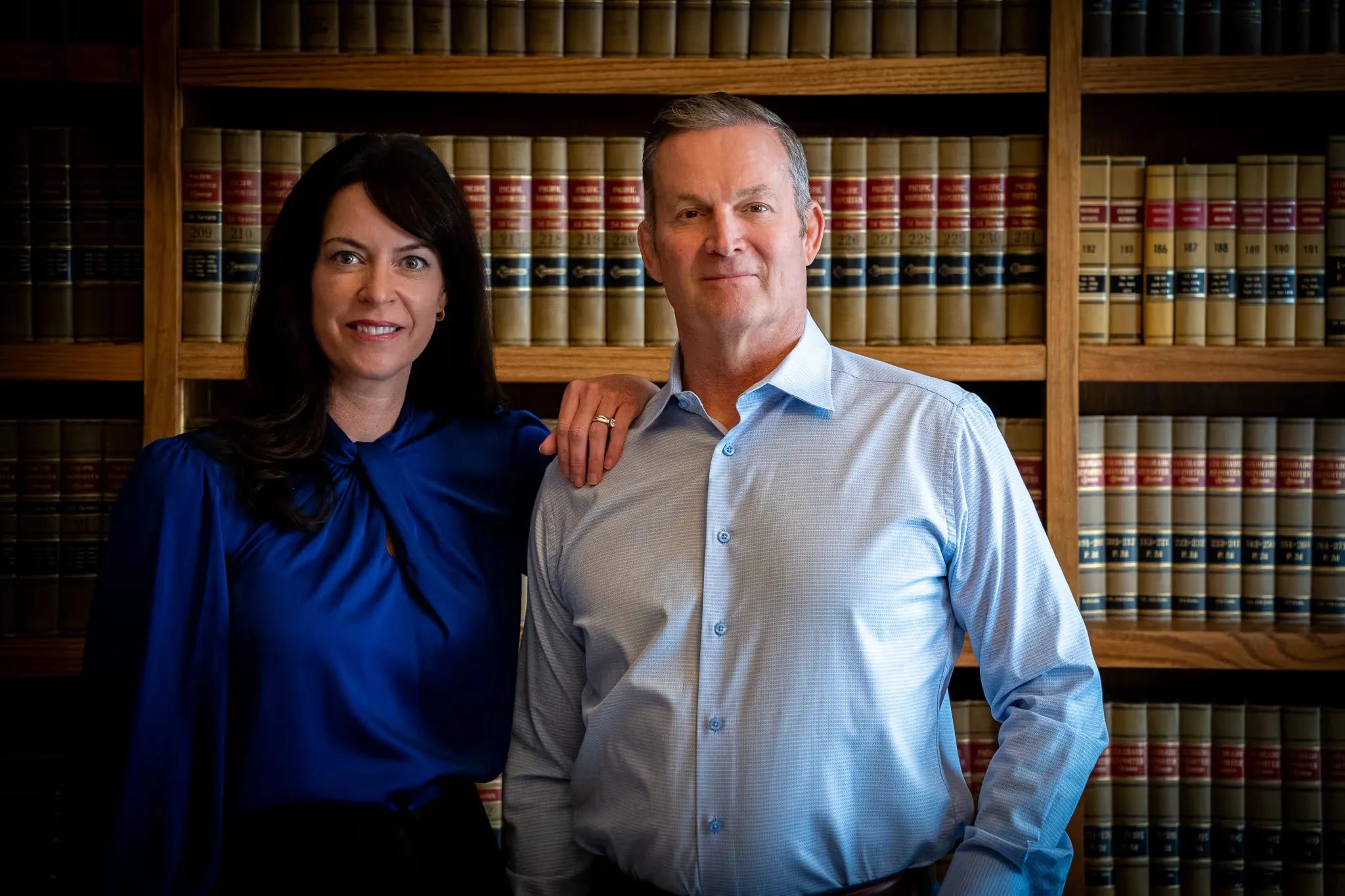 Colleen S. Nelson with a hand on Mark W. Nelson's shoulder, the founders of Nelson Law Firm in the firm's Denver law library