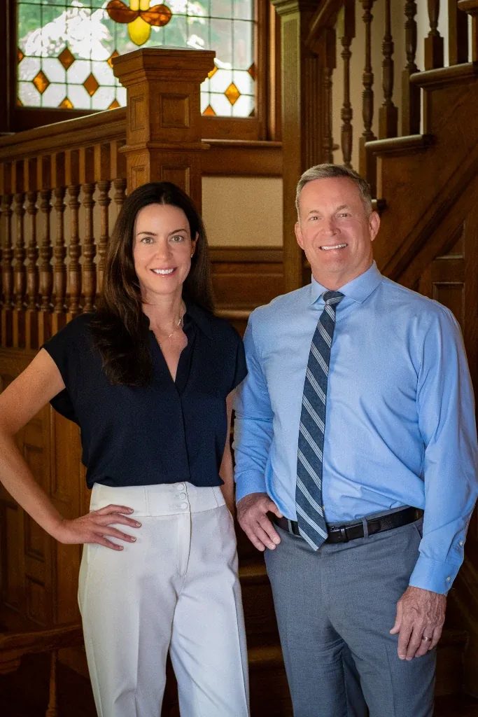 Colleen S. Nelson and Mark W. Nelson, founders of Nelson Law Firm, standing at the oak staircase of the firm's Denver office