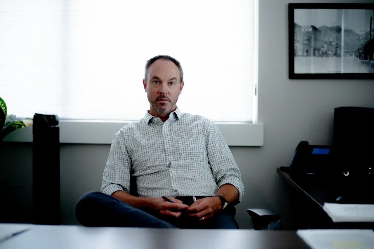 A staff member in a checked shirt sits back in an office chair looking at the camera in a Wick & Trautwein office in Fort Collins.
