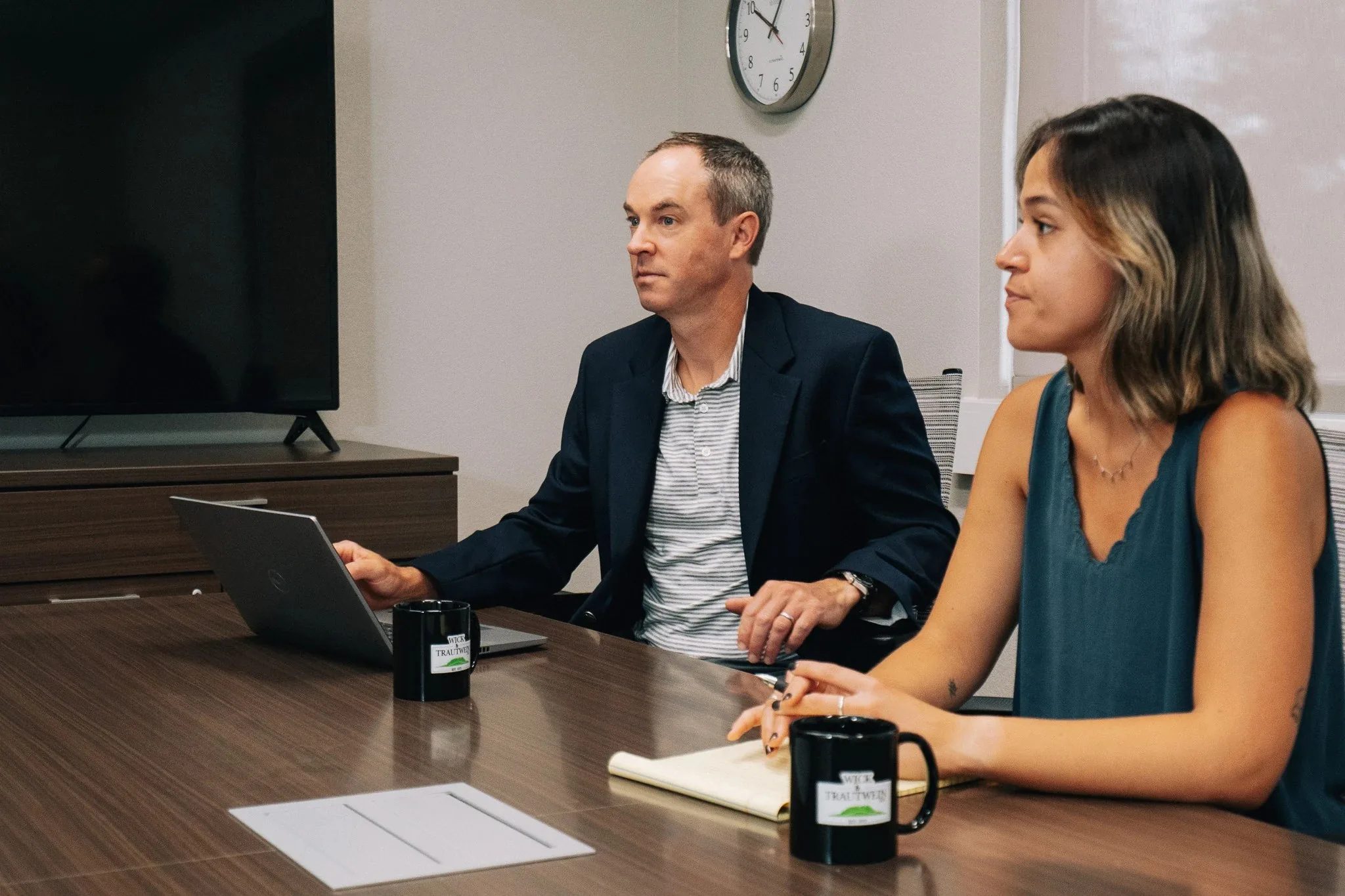 Two staff members at a conference table in the Wick & Trautwein office in Fort Collins, one at a laptop and one taking notes on a legal pad.
