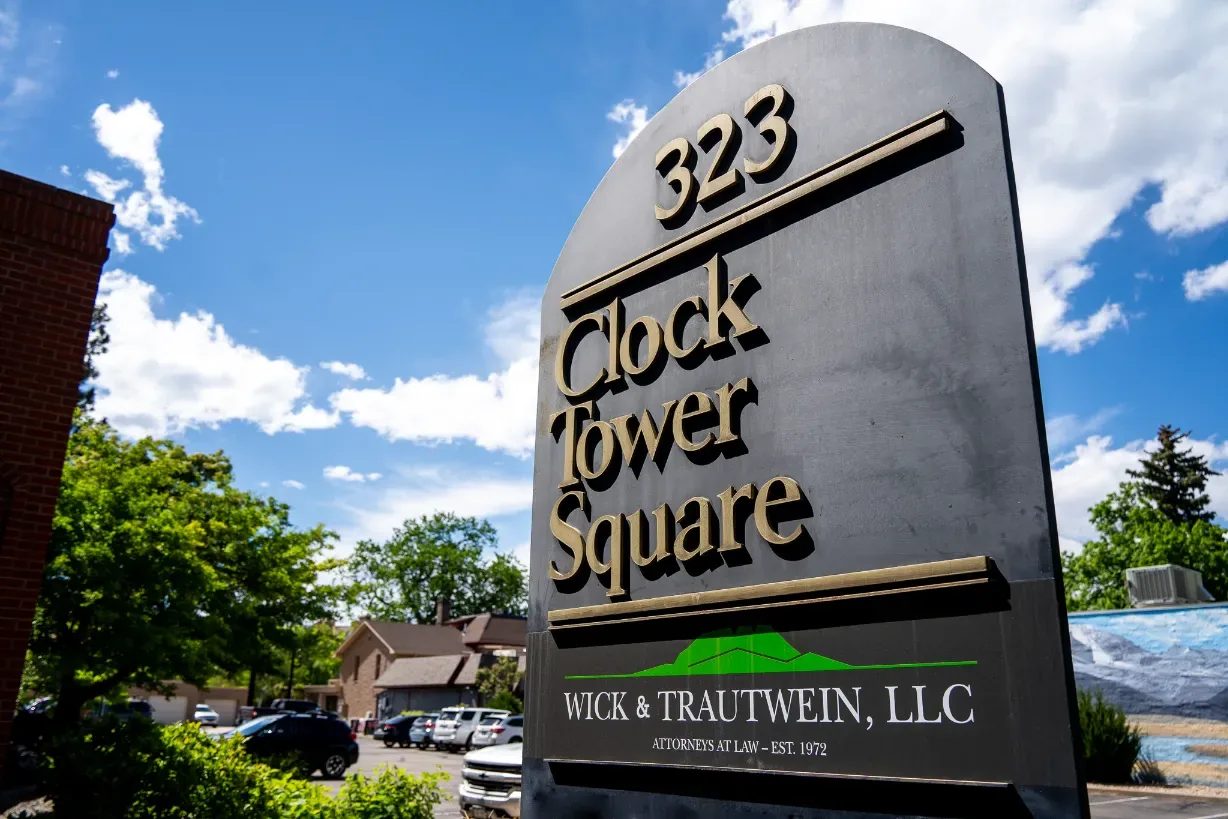 323 Clock Tower Square monument sign with a Wick & Trautwein, LLC Attorneys at Law panel, against a blue sky in Fort Collins.